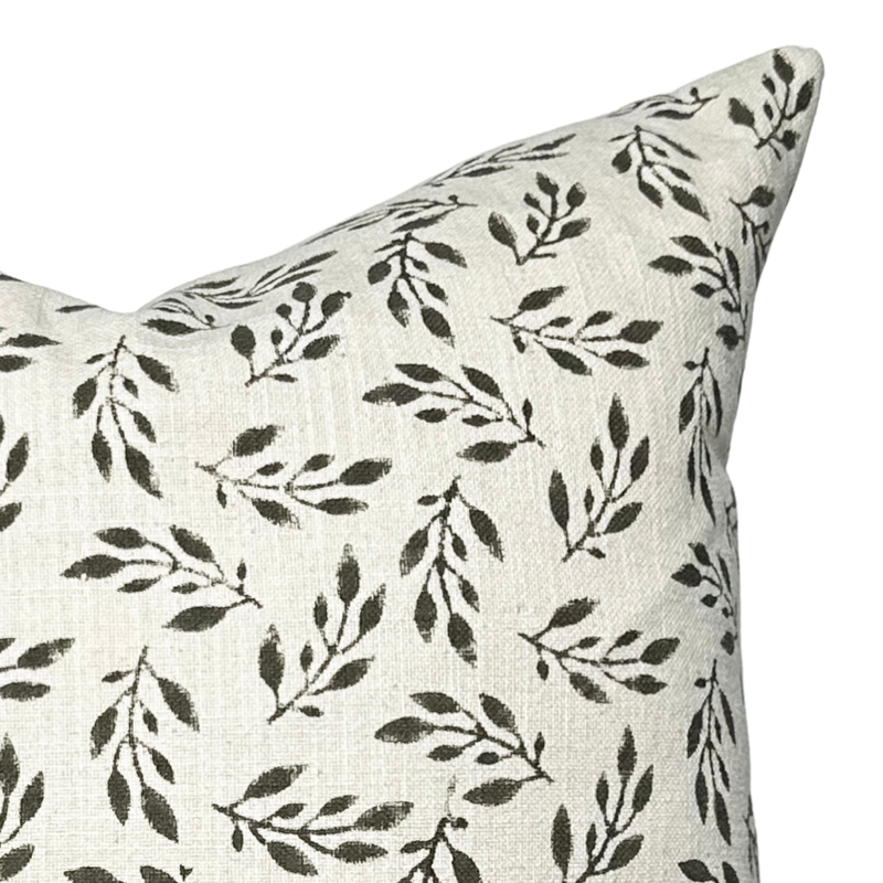 Decorative pillow with black leaf pattern on a light background
