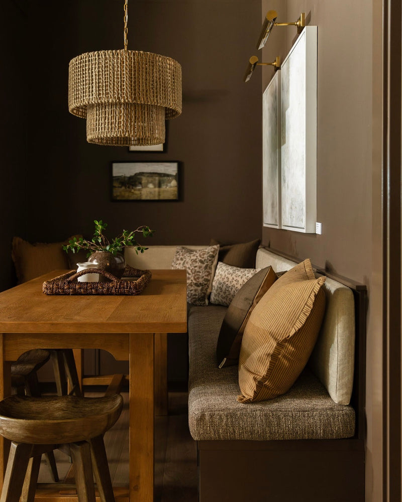 Dining room with wooden table, cushioned bench, and decorative pillows.