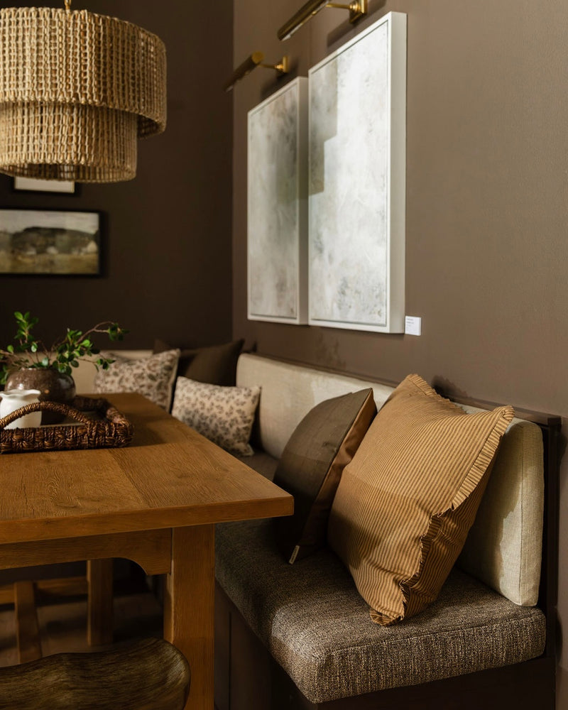 Cozy dining room with wooden table, cushioned bench, and framed artwork on the wall.