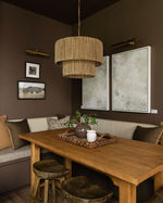 Dining room with wooden table, chairs, and a wicker pendant light.