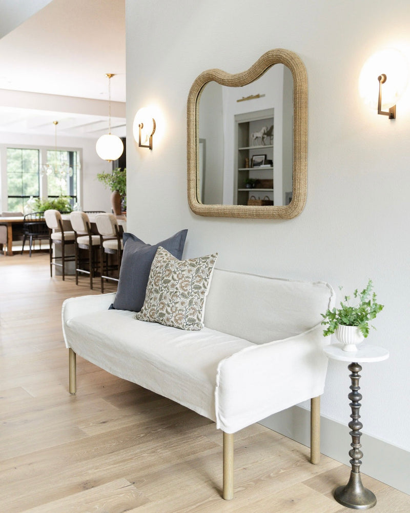 Modern living room with a white sofa, decorative pillows, and a wall mirror.