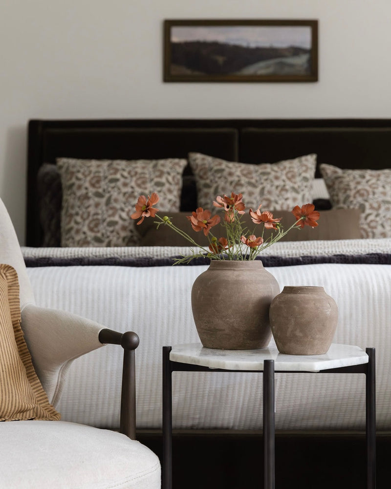 Living room with a sofa, armchair, and decorative vases on a side table.