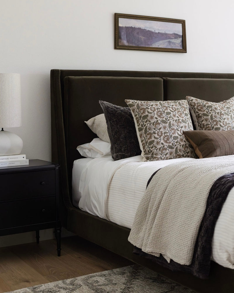 Bedroom with a bed featuring patterned pillows and a nightstand.