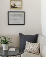 Living room with a couch, table, and framed artwork on the wall.