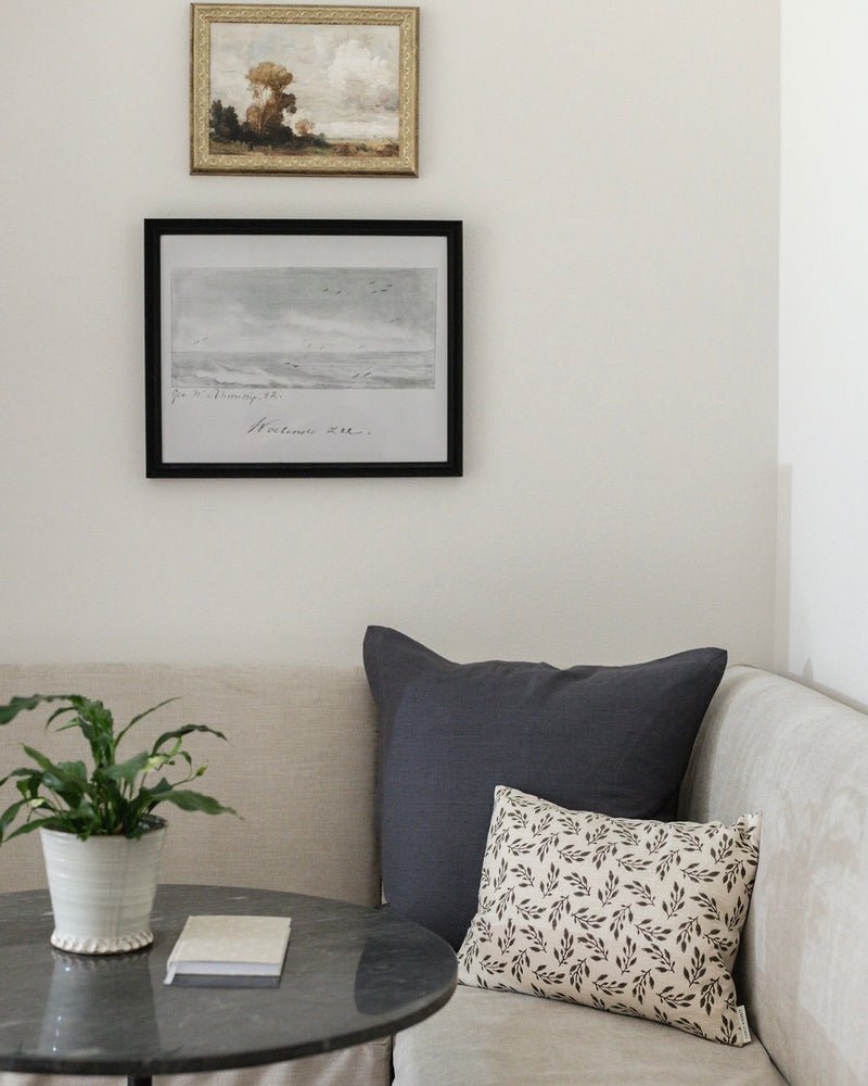 Living room with a couch, table, and framed artwork on the wall.