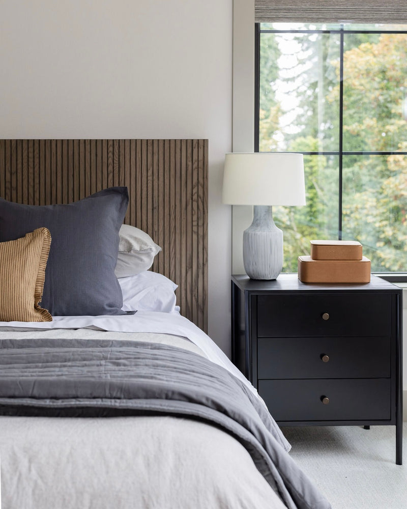 Modern bedroom with a bed, nightstand, and lamp.