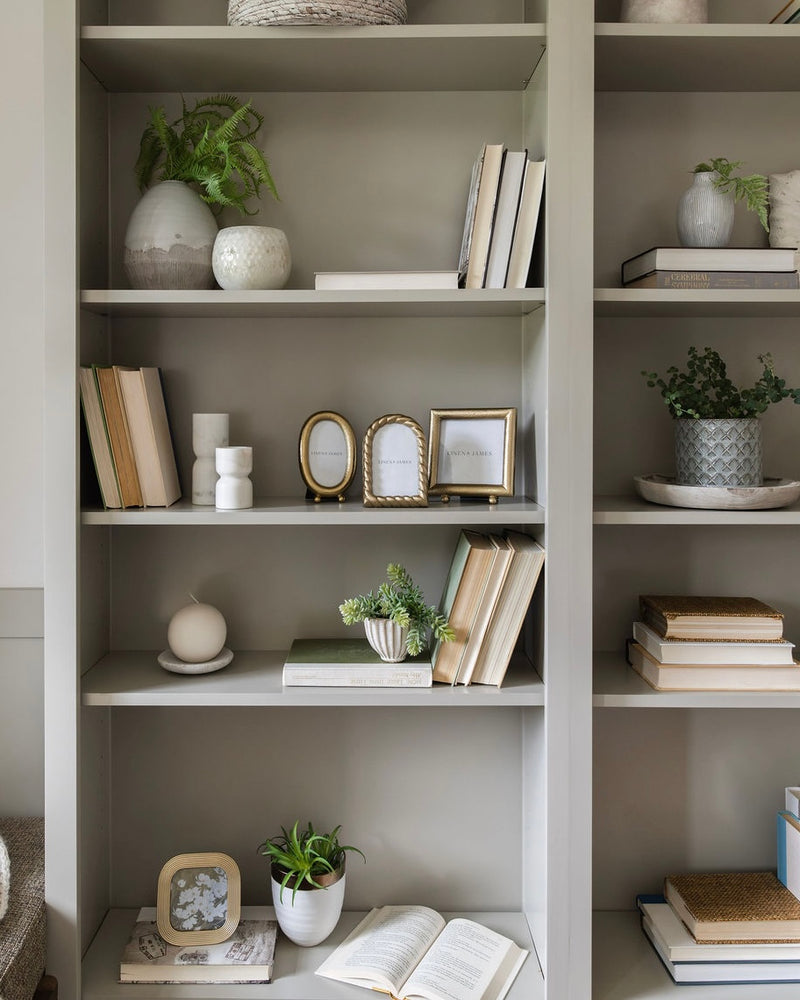 Bookshelf with decorative items including books, plants, and small frames.