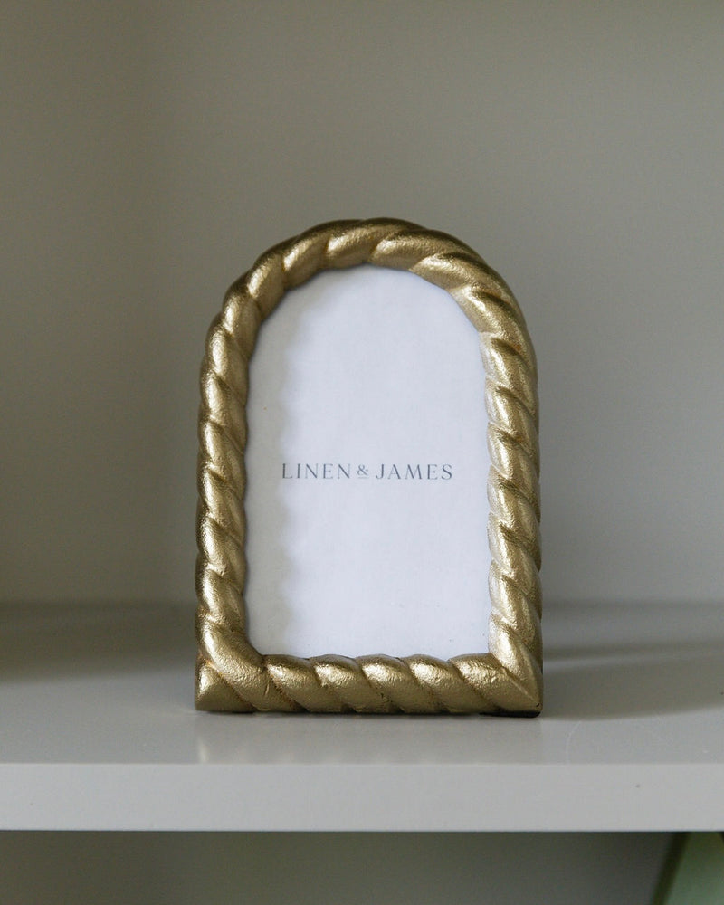 Gold rope-style picture frame on a white surface with a neutral background