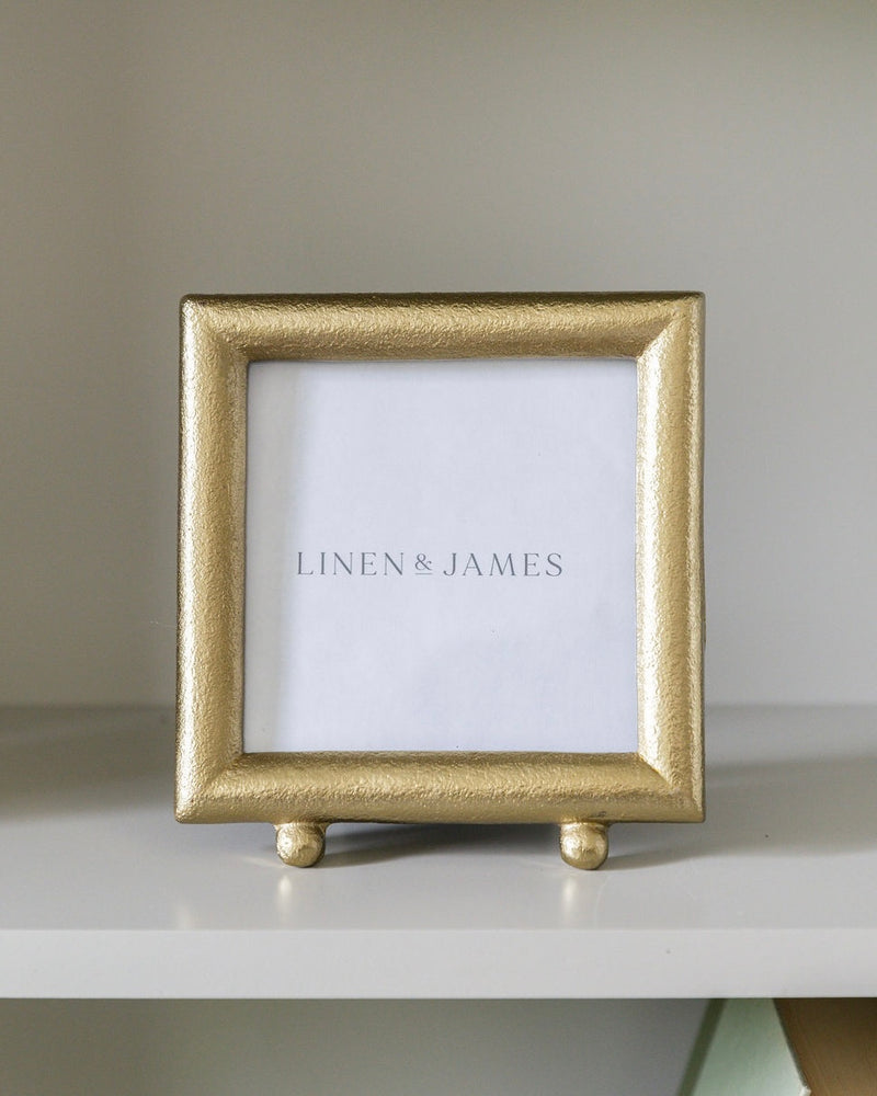 Gold picture frame with 'Linen & James' branding on a white surface.