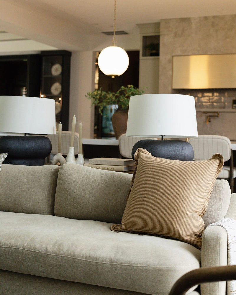 Living room with beige sofa, decorative pillows, and white lamps.
